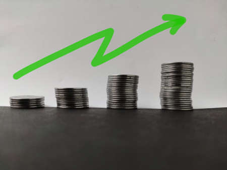 Increasing piles of coins with going up trend. Concept for bullish market and economy growthの写真素材