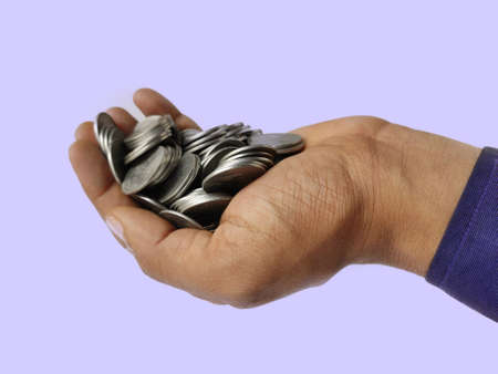 Silver coins in hand side view on blue backgroundの写真素材