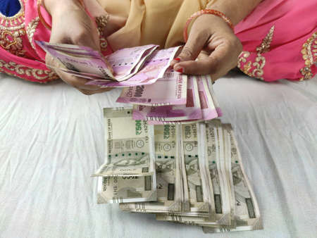 money notes counting by woman hands , indian rupees notes and coins backgroundの写真素材