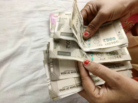 money notes counting by woman hands , indian rupees notes and coins backgroundの写真素材