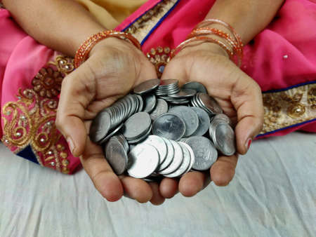 Woman hands full of indian coins , Selective Focus.の写真素材