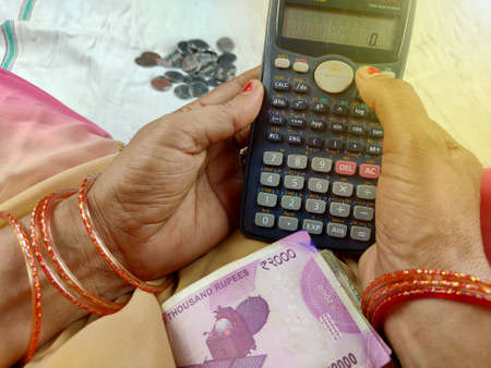 Indian woman counting bank notes using calculatorの写真素材
