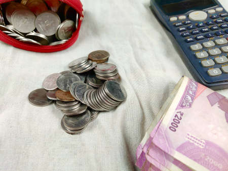 Coins and notes counting or calculation by calculator on white background , budget tax accounting Conceptの写真素材