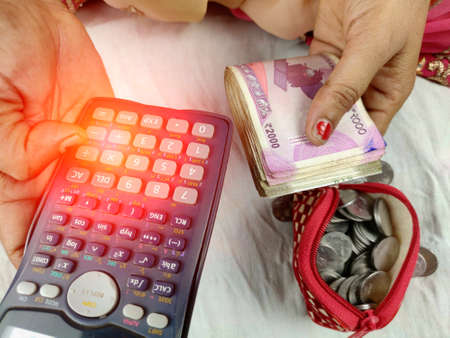 Indian woman counting bank notes using calculatorの写真素材