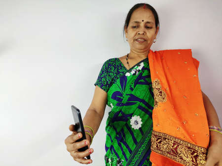 Woman showing new gifted sari on mobile video call to family and friends , thanks giving concept. Indian woman in talking on smart phone.の写真素材