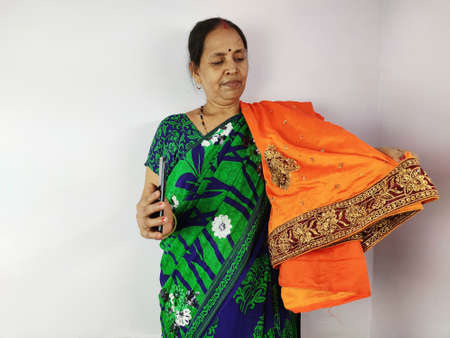 Woman showing new gifted sari on mobile video call to family and friends , thanks giving concept. Indian woman in talking on smart phone.の写真素材