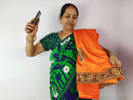 Woman showing new gifted sari on mobile video call to family and friends , thanks giving concept. Indian woman in talking on smart phone.の写真素材
