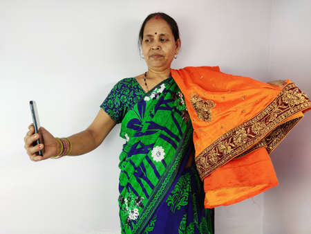 Woman showing new gifted sari on mobile video call to family and friends , thanks giving concept. Indian woman in talking on smart phone.の写真素材