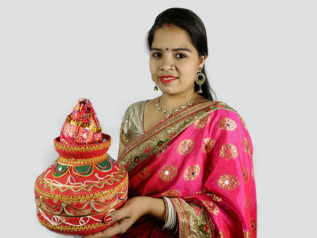 Decorated Earthen pot and coconut in hand on woman in traditional attire