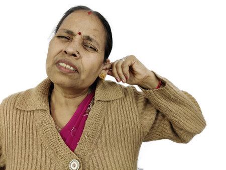 Woman using her finger to scratch ear due to ear pain or earache on white background isolatedの写真素材