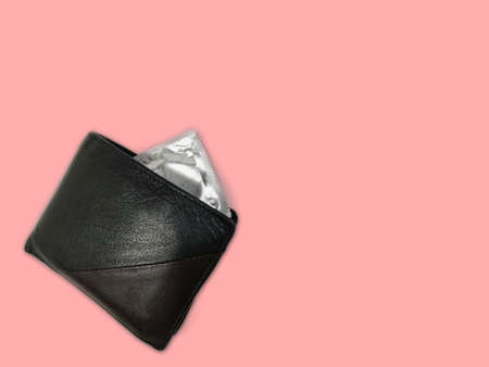 Man wallet or purse with Condom packet against pink background , contraceptive use concept for safe sex with space for text.の写真素材