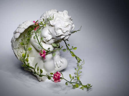 a angel made of clay has a green chaplet arround her neck with red bloomsの写真素材