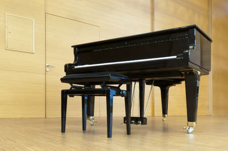black concert paino is standing on a wooden stage with stool ready for playingの写真素材