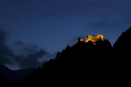 illuminated old ruin on the top of a hill at nightの写真素材