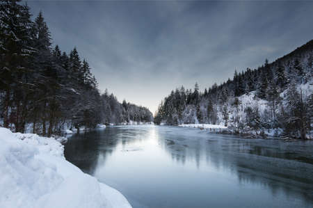 view to a winter landscape with frozen lake plansee and snowy forest in tyrol austria