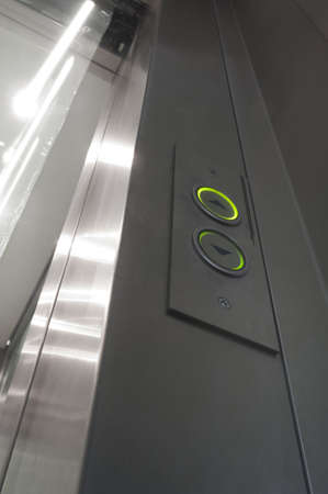 green illuminated elevator buttons and glass and aluminium door opening