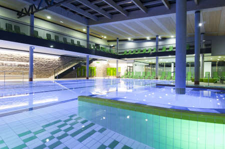 filled indoor swimming pool with colored tiles and illuminationの写真素材