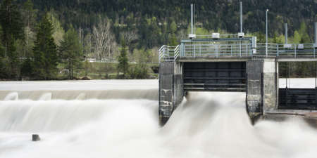 old weir plant with flowing water and trees in background with watergateの写真素材