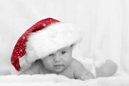 cute newborn baby with red xmas cap lying on white backgroundの写真素材