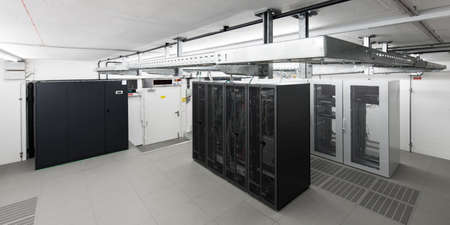 wide angle view of small air conditioned computer room with racks an cable trays
