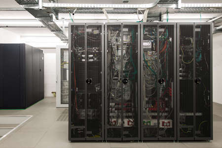 backside of arranged black server racks in small computer roomの写真素材