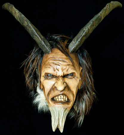 wooden satan evil mask with horns and fur beard on black