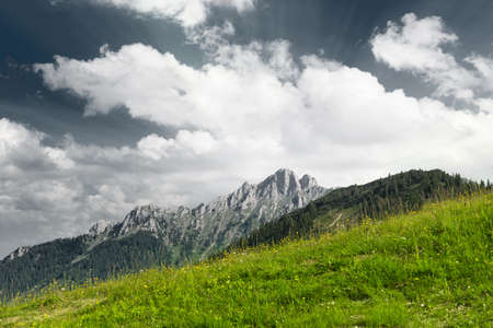 green mountain meadow with mountain peak and clouds