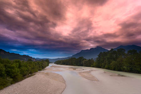 surreal red sky before storm at river in green forestの写真素材