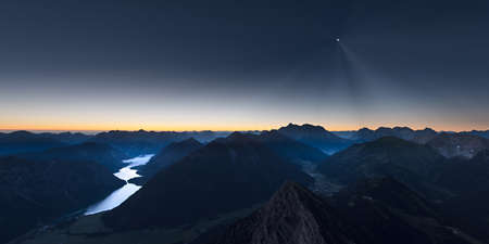 sunrise in mountains of austrian alps with moonlight and reflecting lake