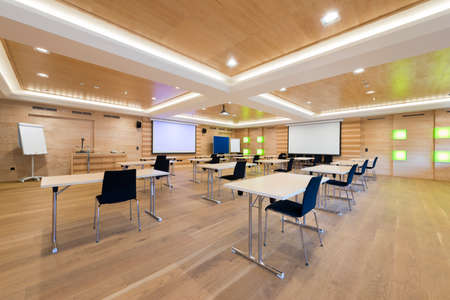 tables and chairs in modern wooden conference room with projection screensの写真素材