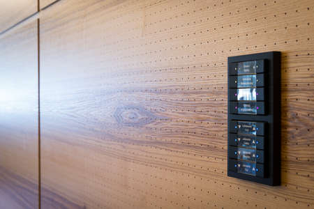 black switches for light control on wooden acoustic wall