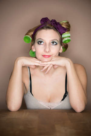 musing thoughtful girl with hair curler at table