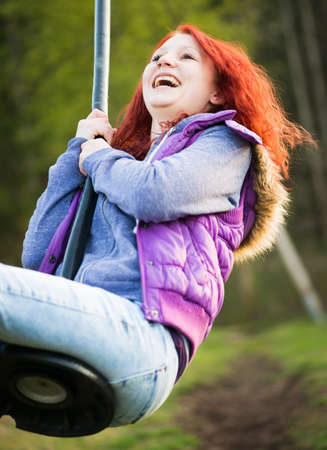 young lucky girl is laughing while she swings at playgroundの写真素材