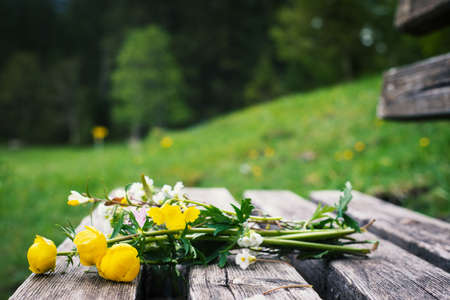 romantic bunch of yellow flowers on old wooden timber benchの写真素材