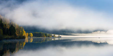 idyllic fall mood at tyrol lake with morning dust and colored forest