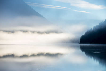 mountain alps lake at fall with mirroring dust abd blue skyの写真素材
