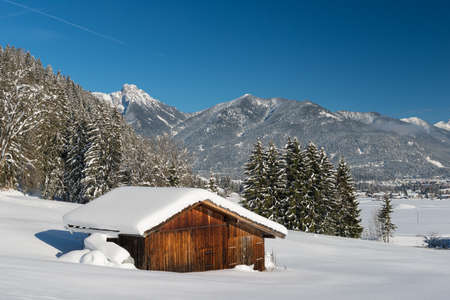 snow landscape in austrian alps with wooden timber shedの写真素材