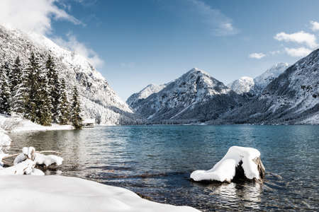 idyllic cold lake at snow mountain landscape in winter sceneryの写真素材