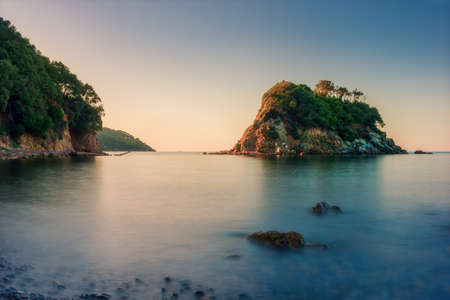 small rocky island while sunrise at ocean in italyの写真素材