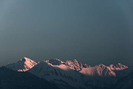 highlighted snowy mountain summits in austria at sunsetの写真素材