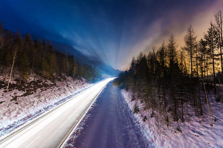 car lights on street at winter night with colorful skyの写真素材