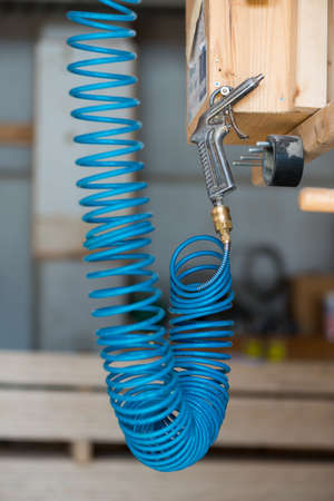 blue compressed pneumatic air hose with pistol hanging at screwの写真素材