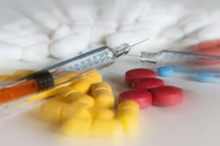 many colored drug pills with injection pins on whiteの写真素材