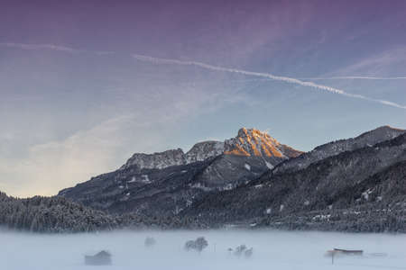 colorful sky at sunrise with huge mountain and foggy meadow