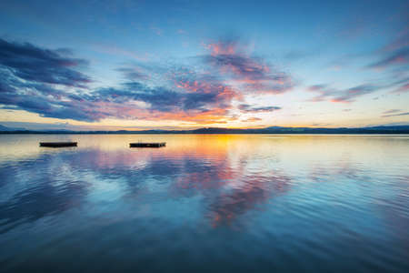colorful sunset clouds at blue lake with wooden plateaus in austriaの写真素材
