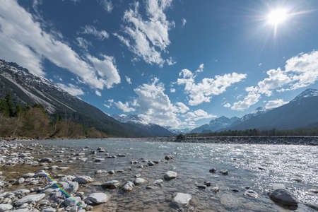 stone bank at flowing river lech in tirol lechtal aith blue sky and sunの写真素材