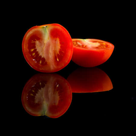 fresh halfed red tomato on black backgroundの写真素材