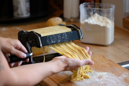 homemade noodles with small manual machine in kitchen with flourの写真素材