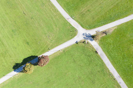 top drone aerial view to crossing road in green meadow with fall treesの写真素材