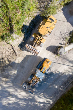top view of two orange wheel-mounted front loader at stone quarryの写真素材